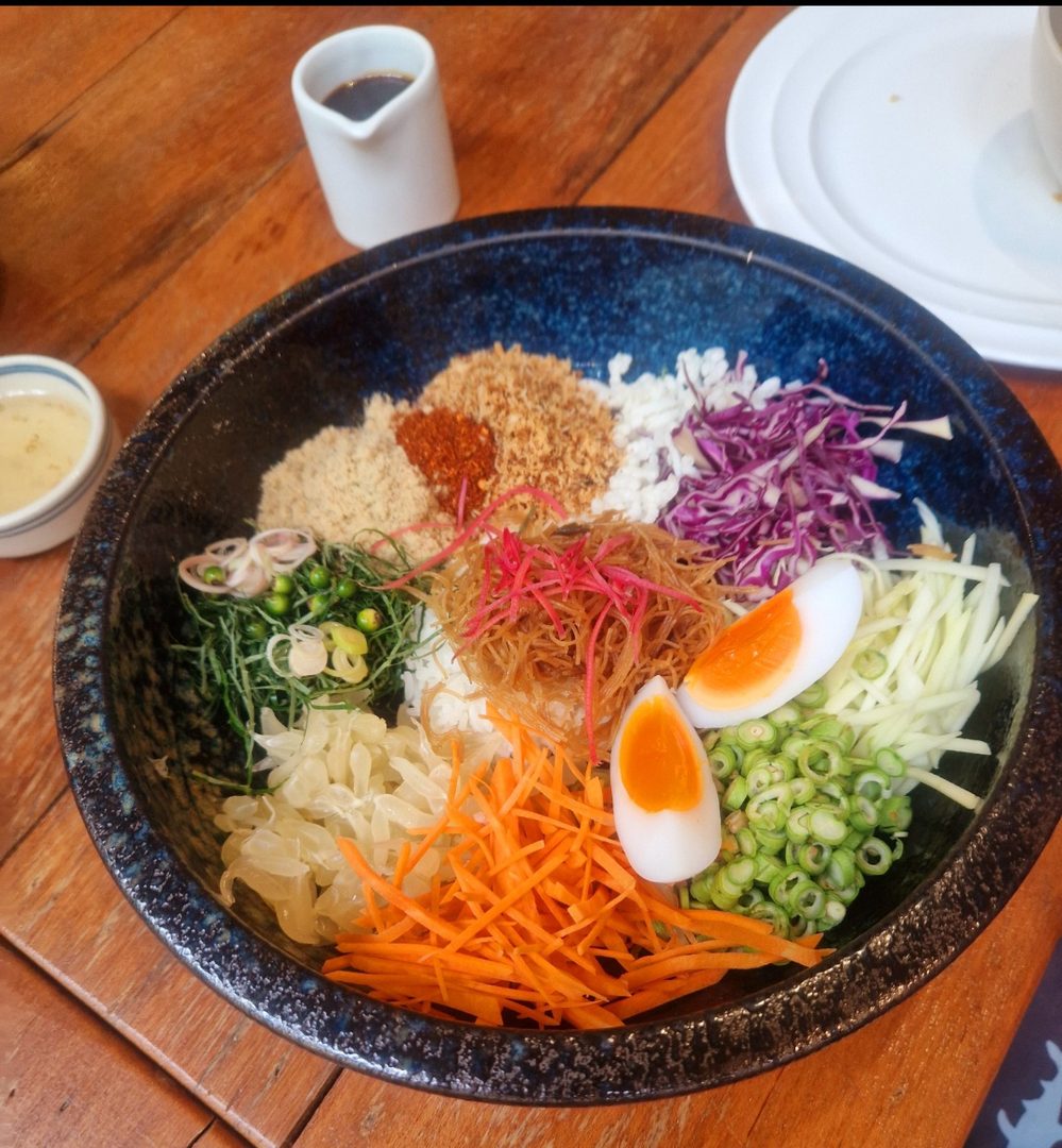 A seasonal rice bowl with soft egg, pickled vegetables and fresh herbs
